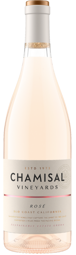 A bottle of Chamisal Vineyards Rosé wine with a clear glass showing pale pink liquid and a cream-colored label featuring the winerys name and details about the wine from SLO Coast, California.