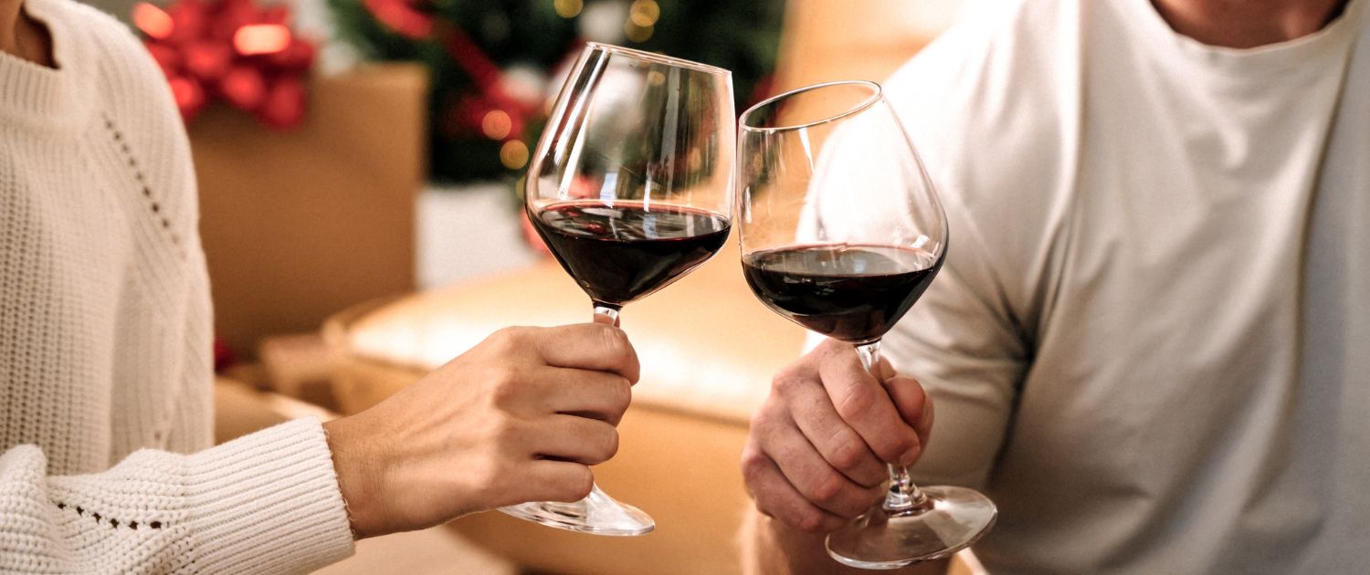 Photo of a man and women drinking wine in front of a tree.